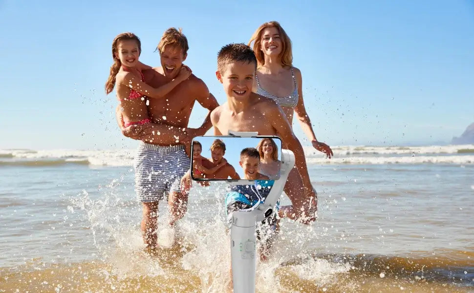 Familia disfrutando en la playa con gimbal estabilizador para móvil 3Ejes para grabar vídeos estables.